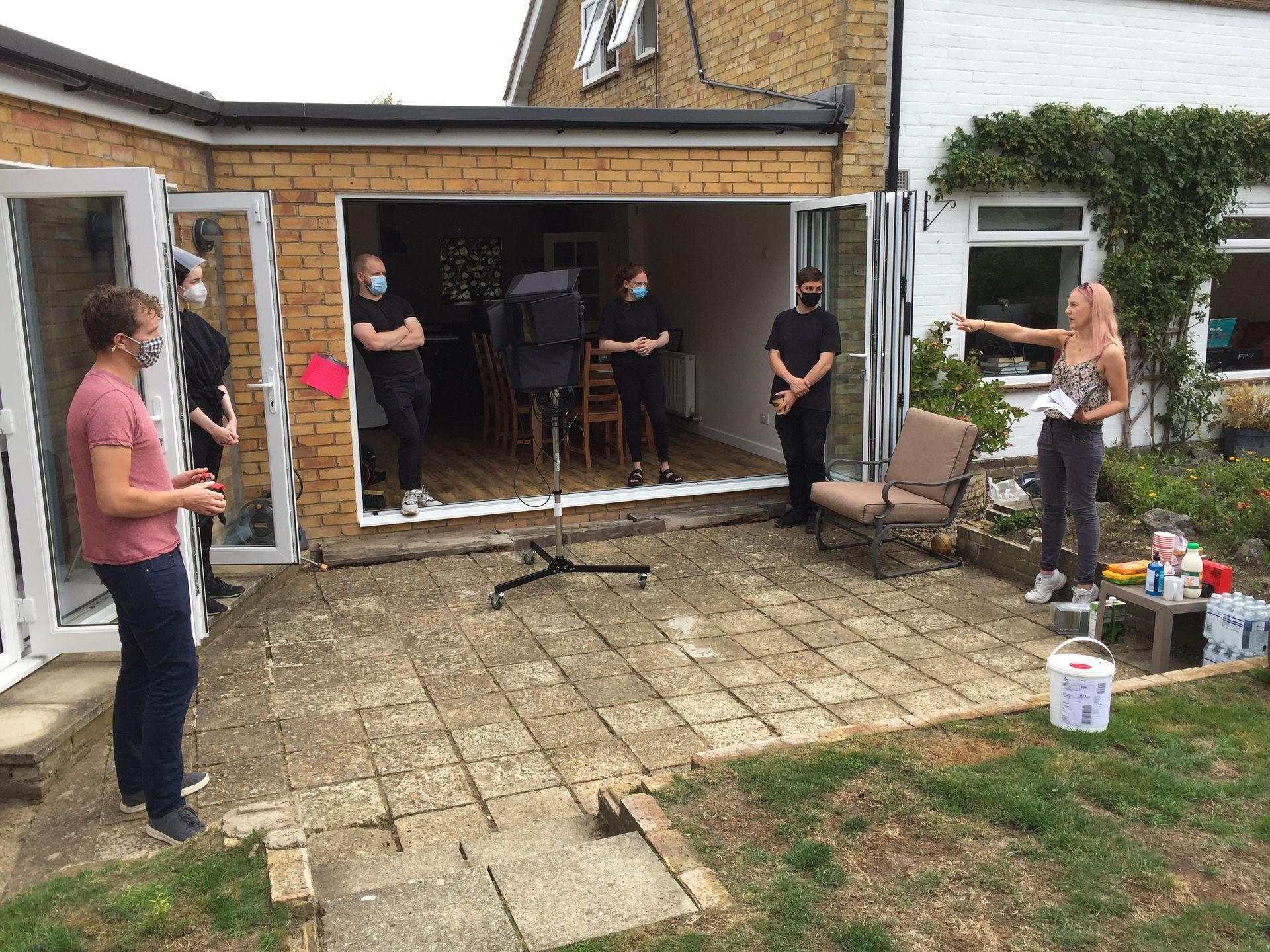 A group of people are standing on a patio in front of a house.