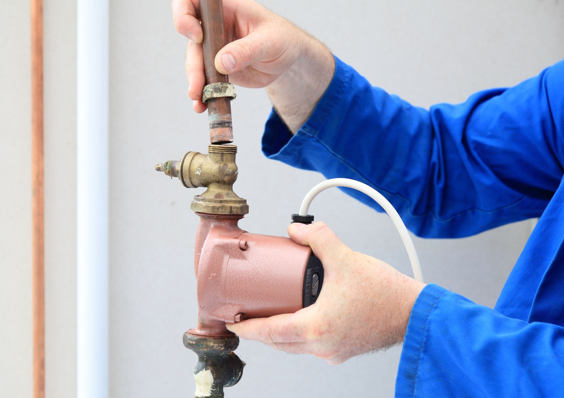 A technician is performing water pump service by connecting a water pipe to a pump.