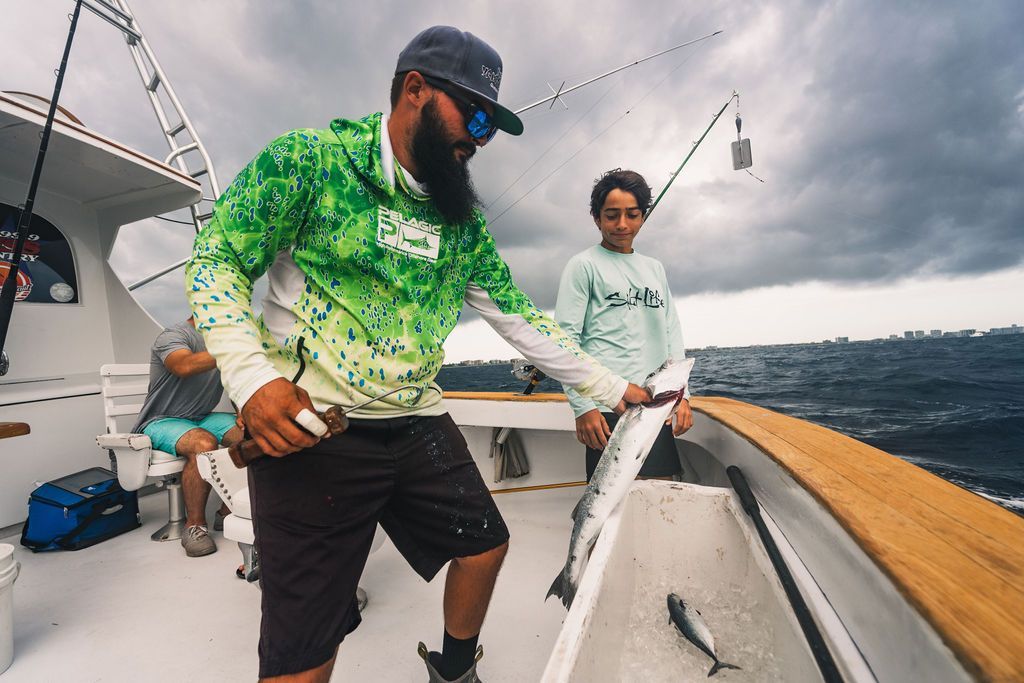 A man and a boy are fishing on a boat.