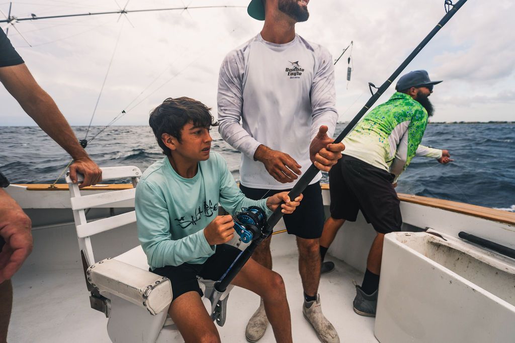 A man and a boy are fishing on a boat.