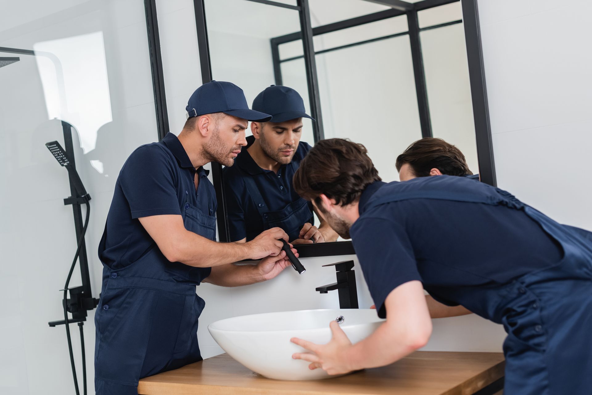Plumbers checking the sink in a bathroom with a flashlight. Plumbers checking the sink in a bathroom with a flashlight.