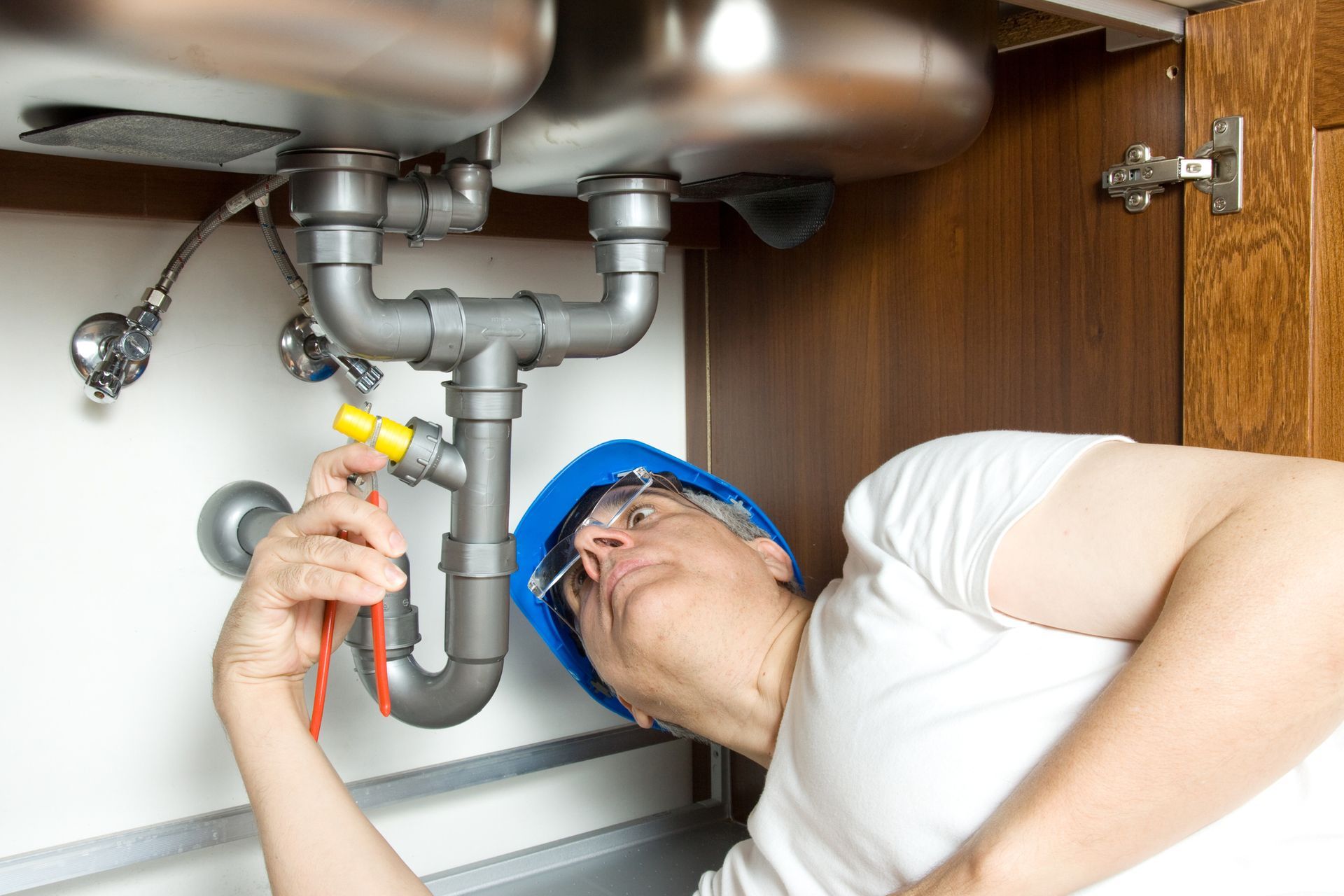 Plumber from Alternative Plumbing Plus Inc. checking plumbing system under the sink in Maumee, OH, e