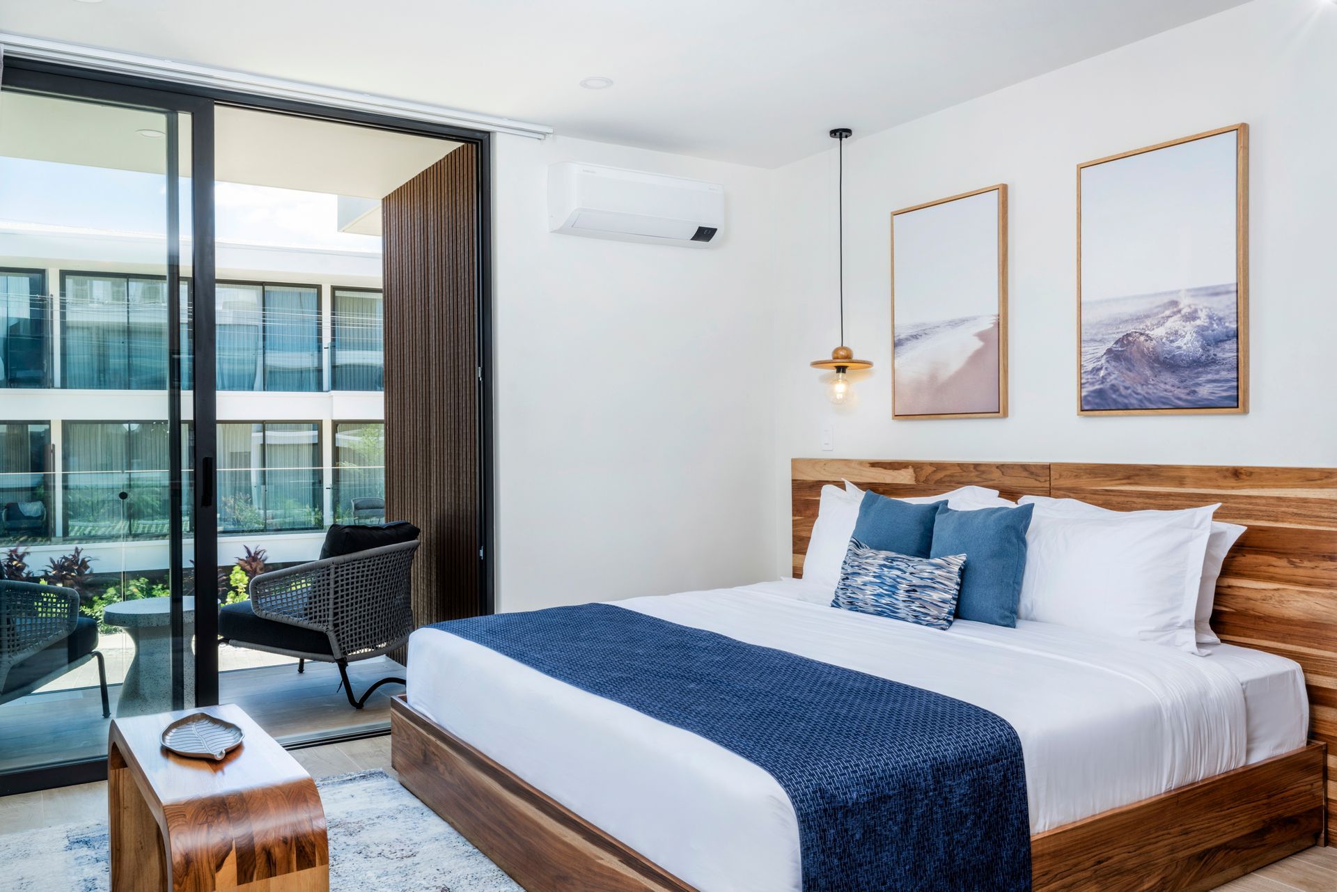 Bright modern bedroom with king bed, blue accents, balcony, and city view