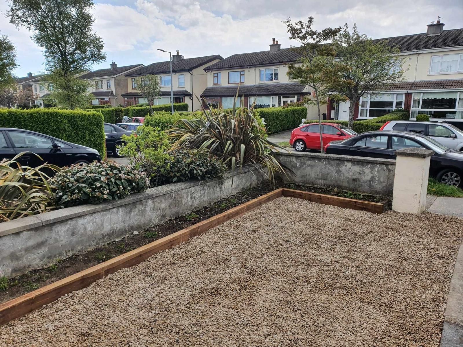 A gravel driveway with cars parked in front of a row of houses.