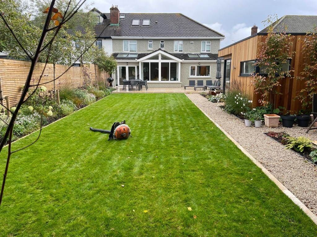 A lawn mower is laying on the grass in front of a large house.