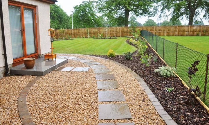 A walkway leading to a house with a fence in the background
