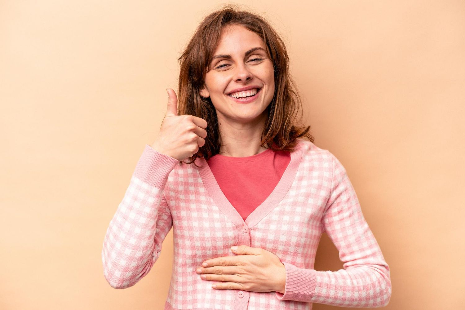 A woman is smiling and giving a thumbs up sign.