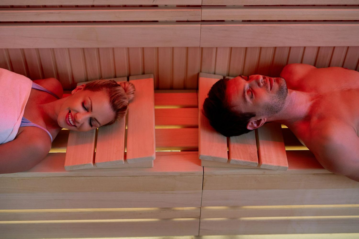 A man and a woman are laying in a sauna.