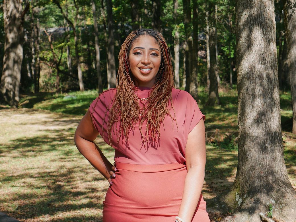 A woman in a pink dress is standing in the woods.