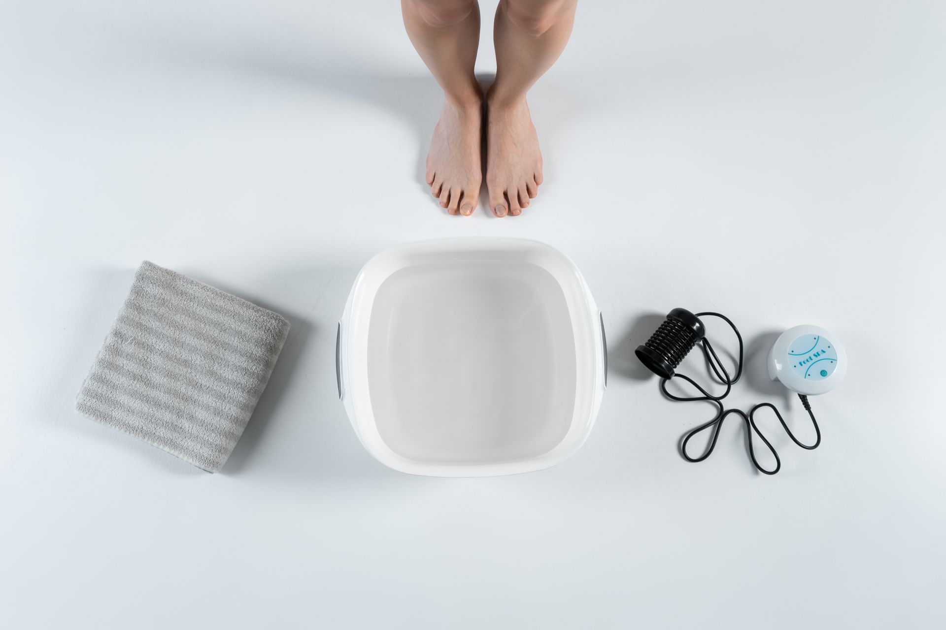 A person is standing next to a bowl of water and a towel.