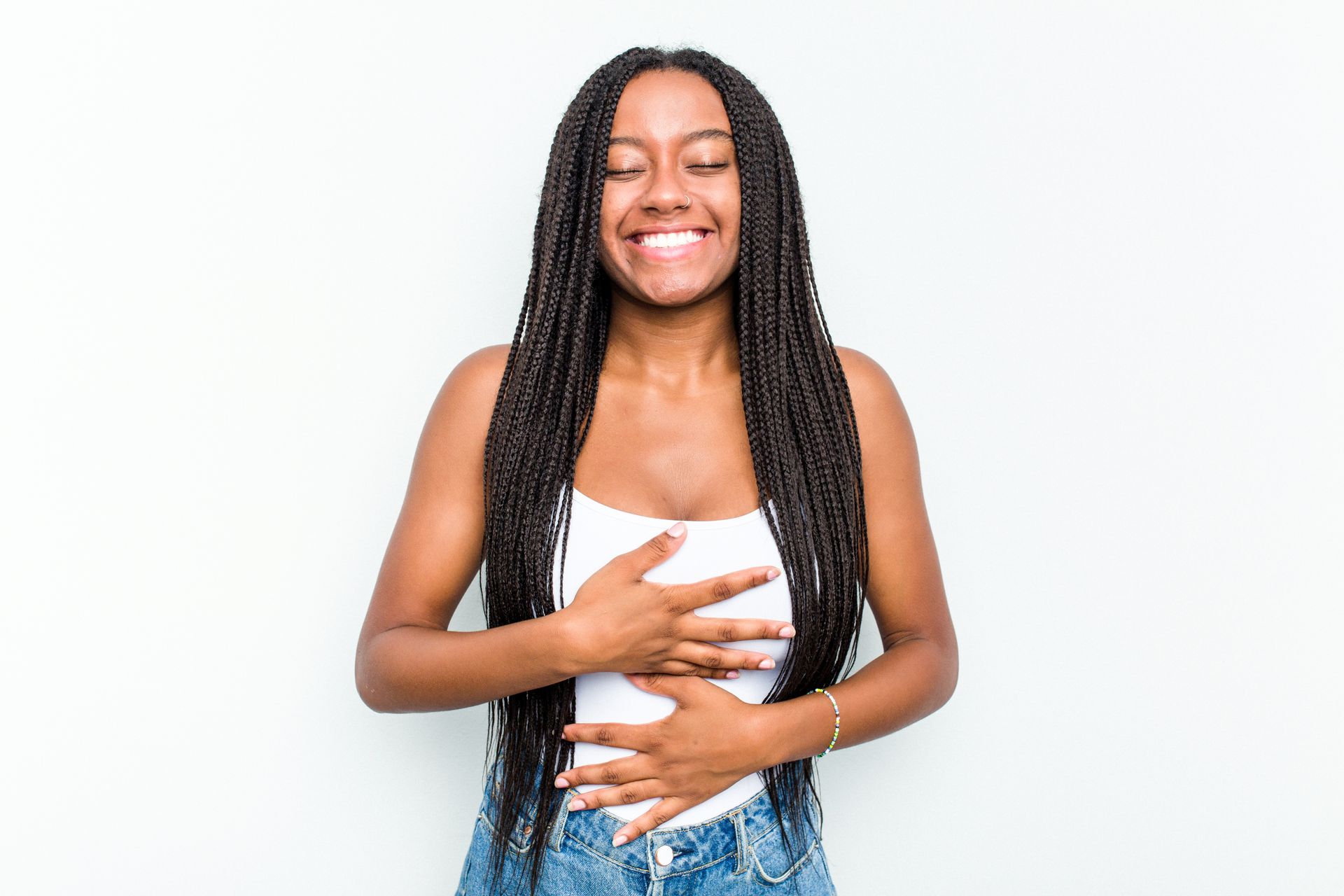 A young woman is holding her belly and smiling.