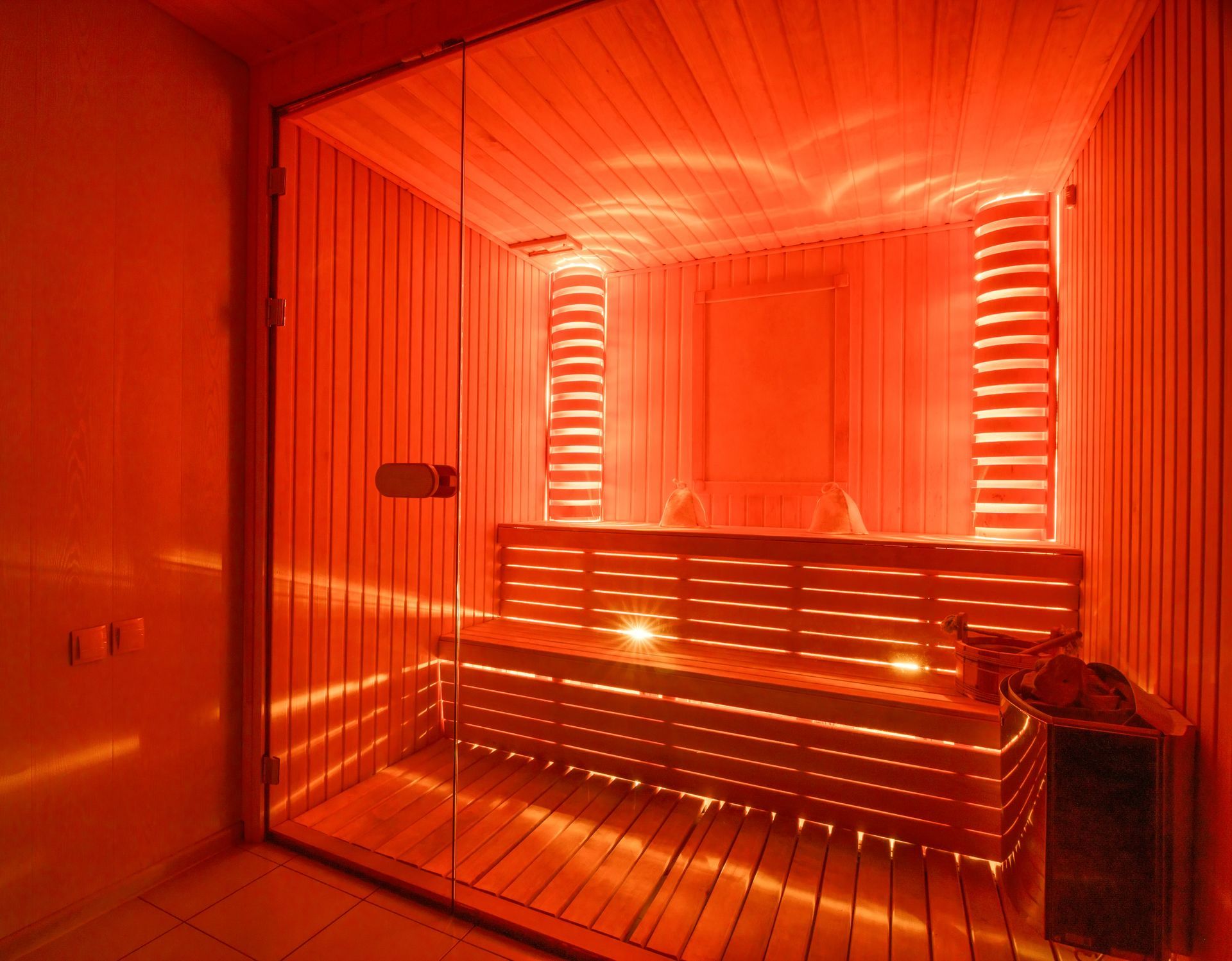 A wooden sauna with red lights on the walls and ceiling.