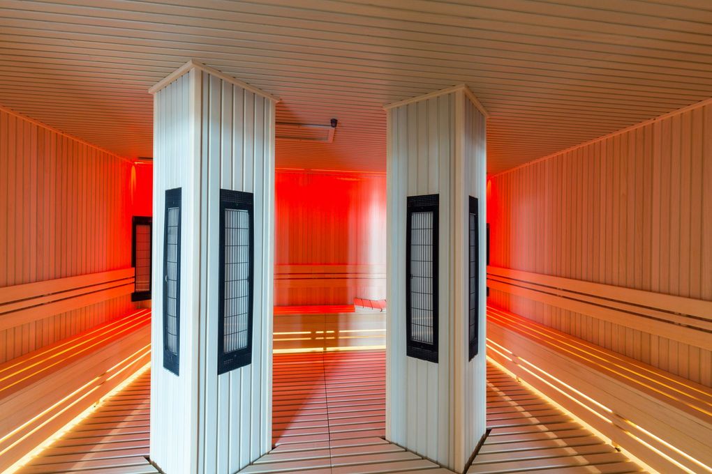 There are two columns in the middle of a sauna with red lights.