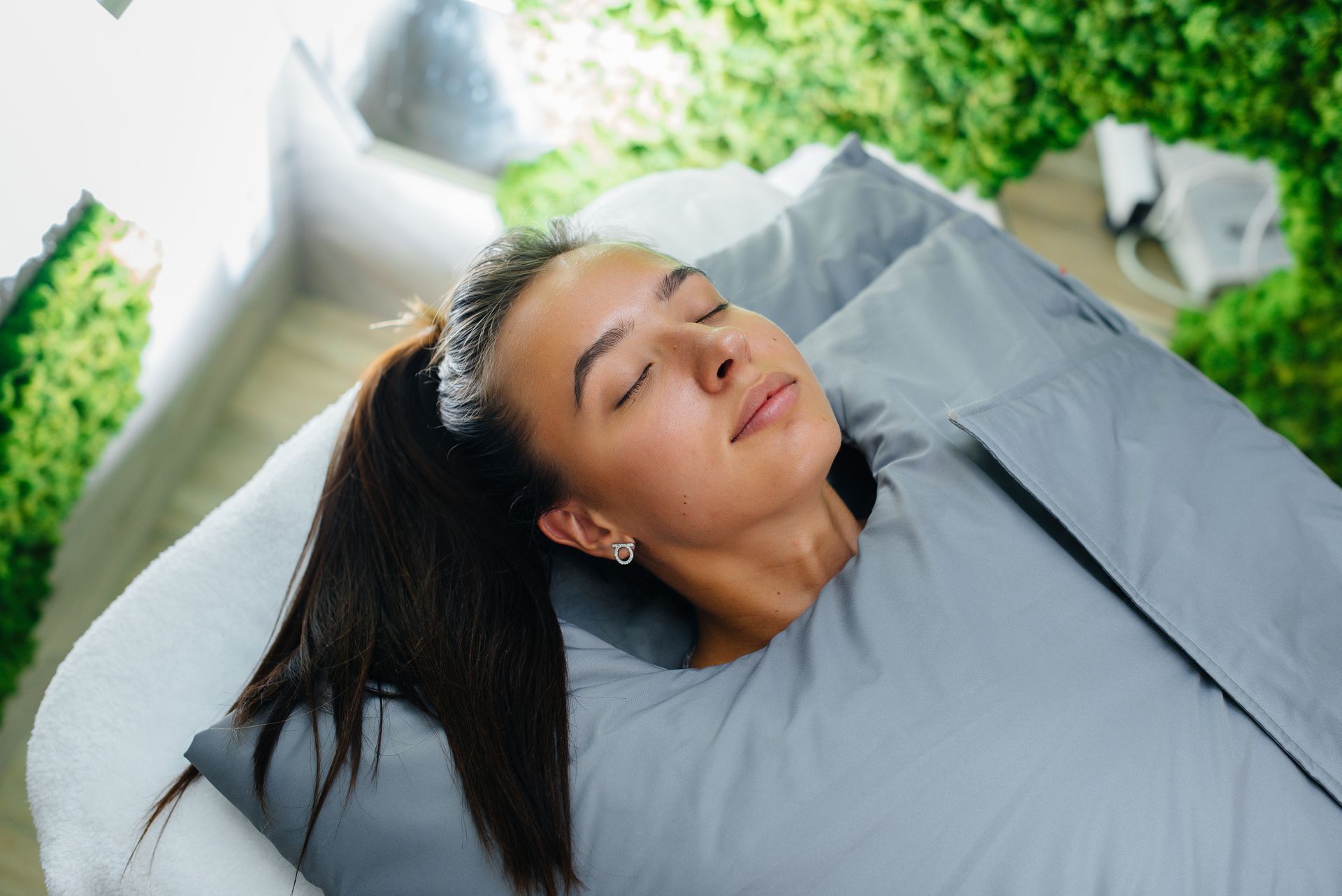 A woman is laying in a blanket on a bed with her eyes closed.