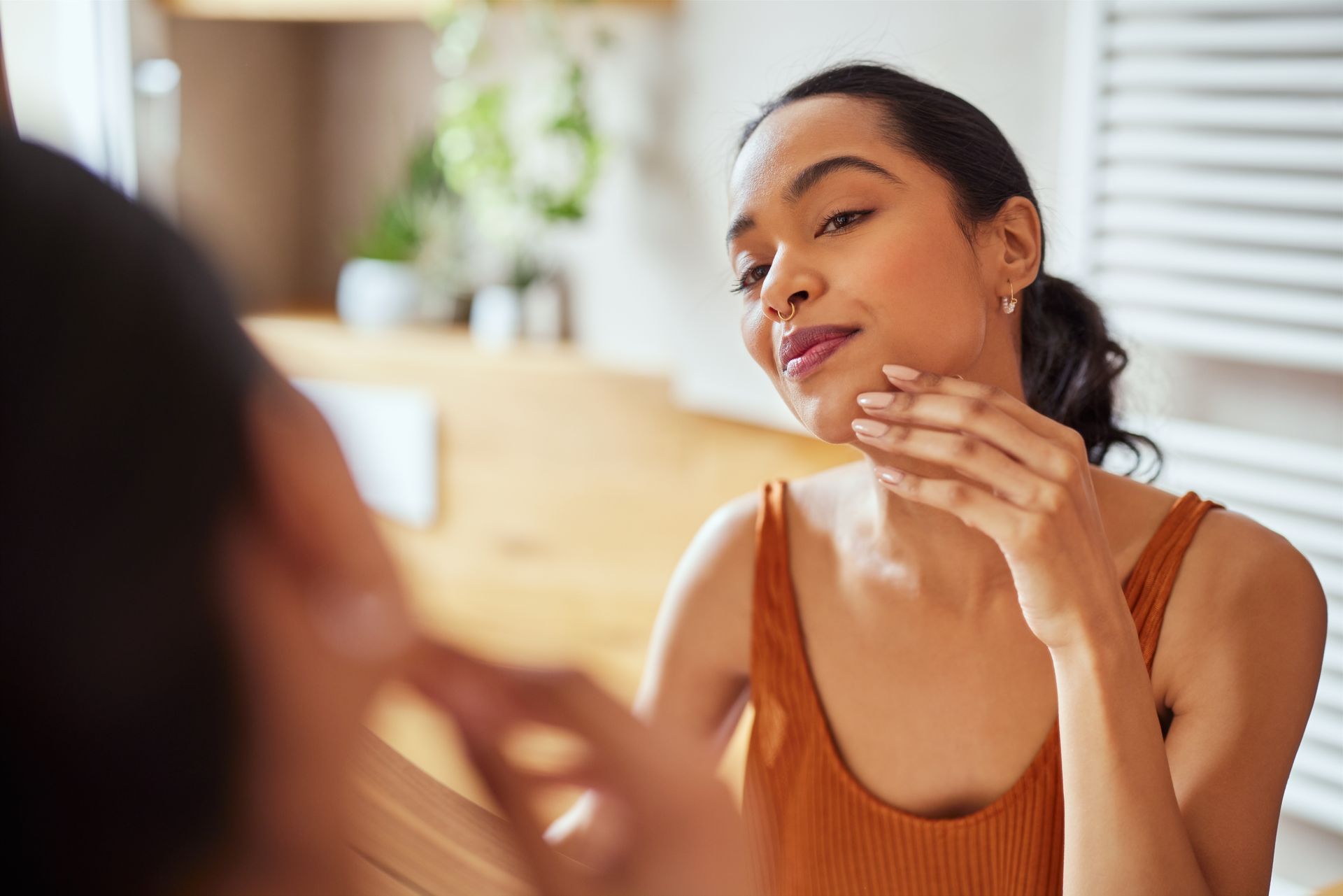 A woman is looking at her face in the mirror.