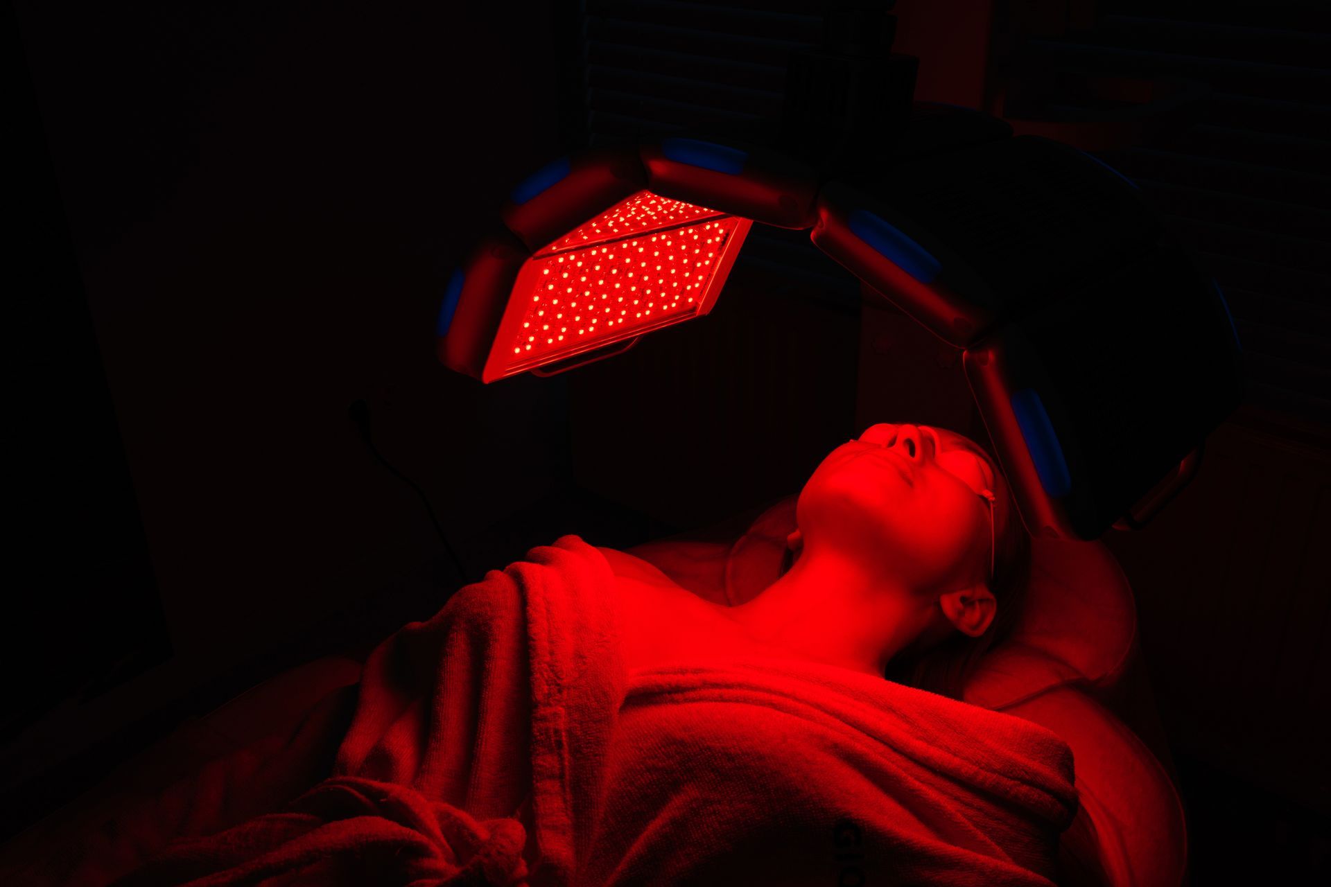 A woman is laying on a bed under a red light.