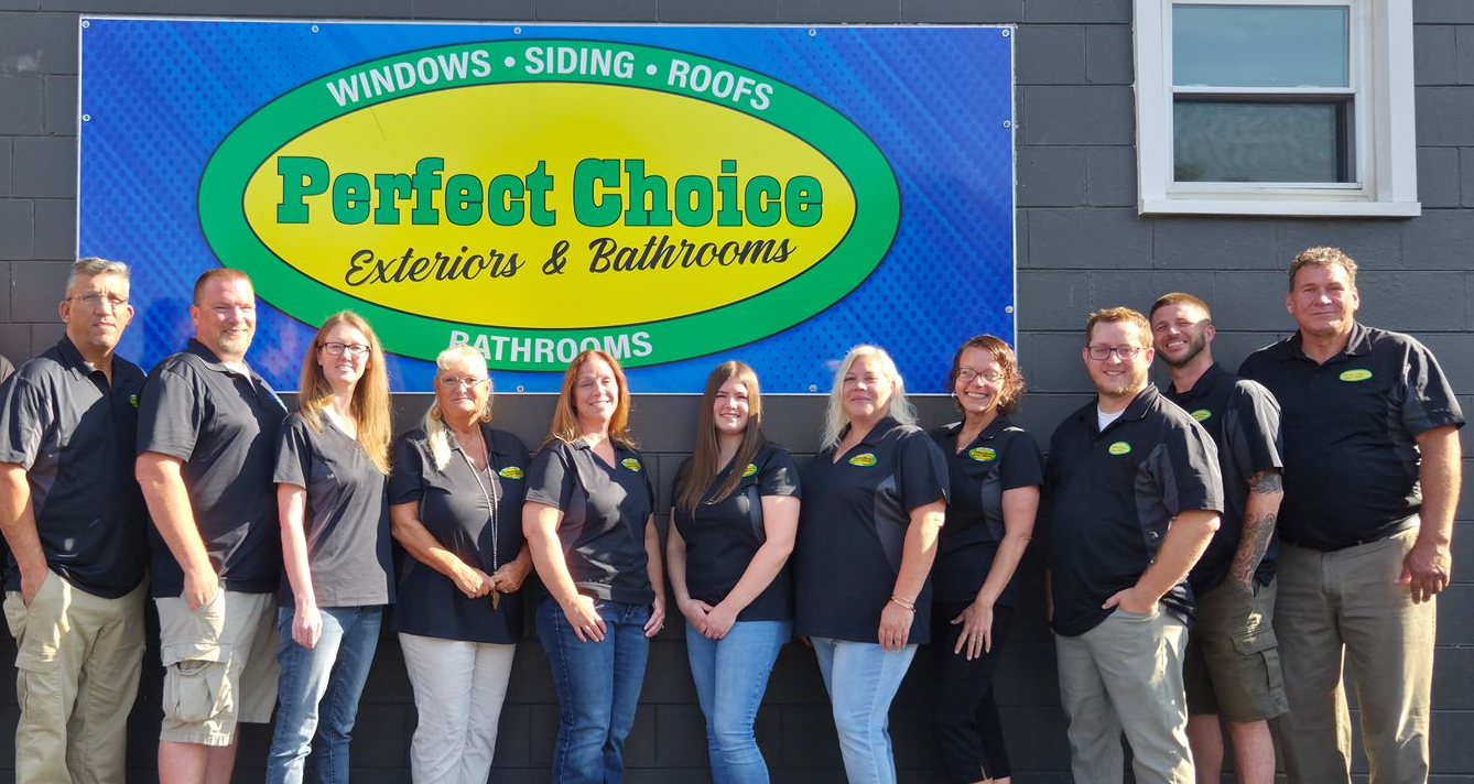 Group of people in black shirts standing in front of a sign for Perfect Choice Exteriors & Bathrooms.