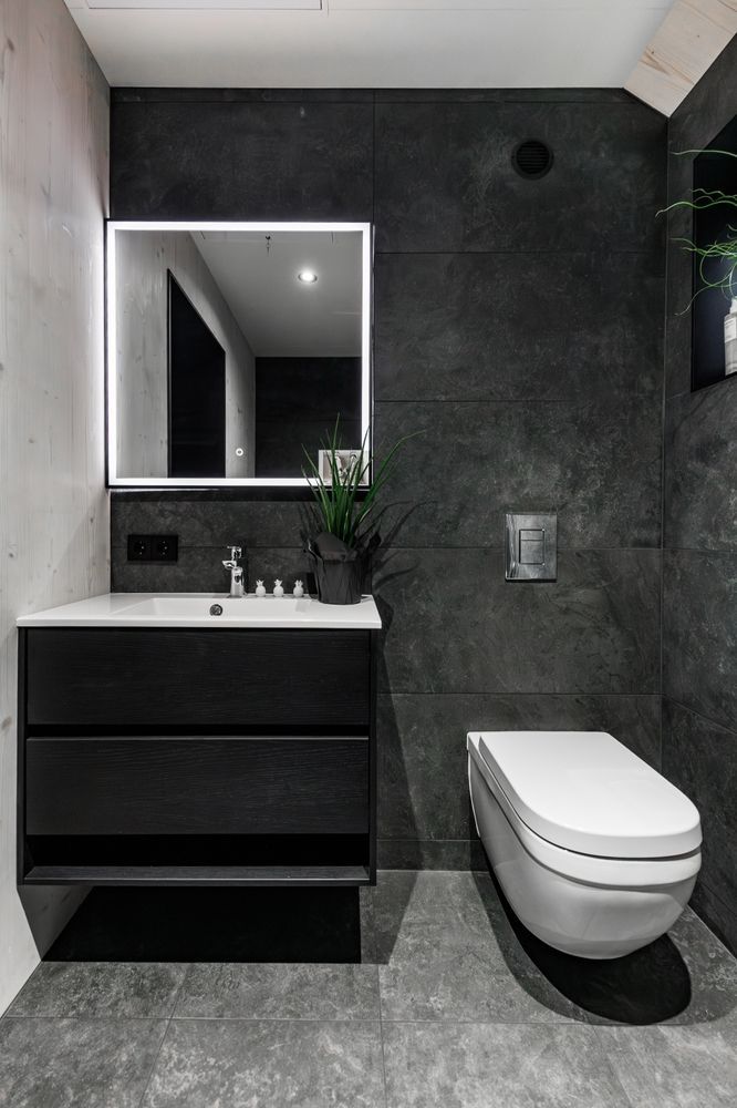 Modern black and gray bathroom with floating toilet, vanity, and mirror.