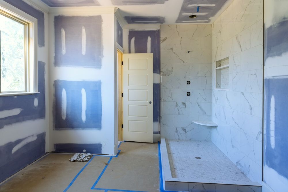Bathroom under construction, drywall, marble shower, and open doorway.
