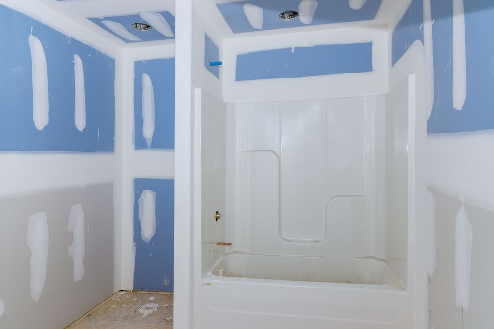Bathroom under construction with blue drywall and white tub.