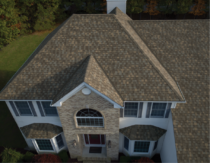 Aerial view of a two-story house with a brown shingled roof and brick facade.