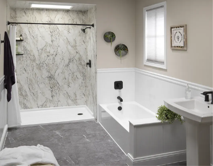Bathroom with white tub, shower, and vanity; gray flooring; marble-look shower wall.