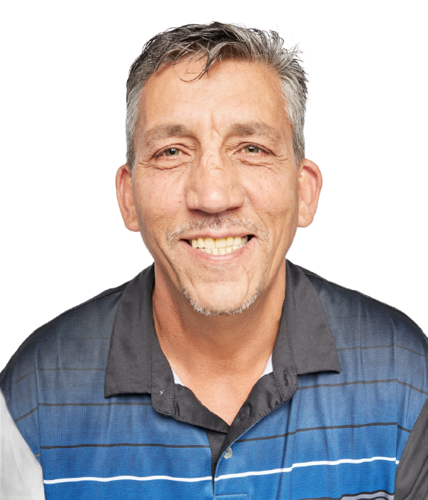 Man smiling, wearing a blue and gray striped polo shirt, white background.