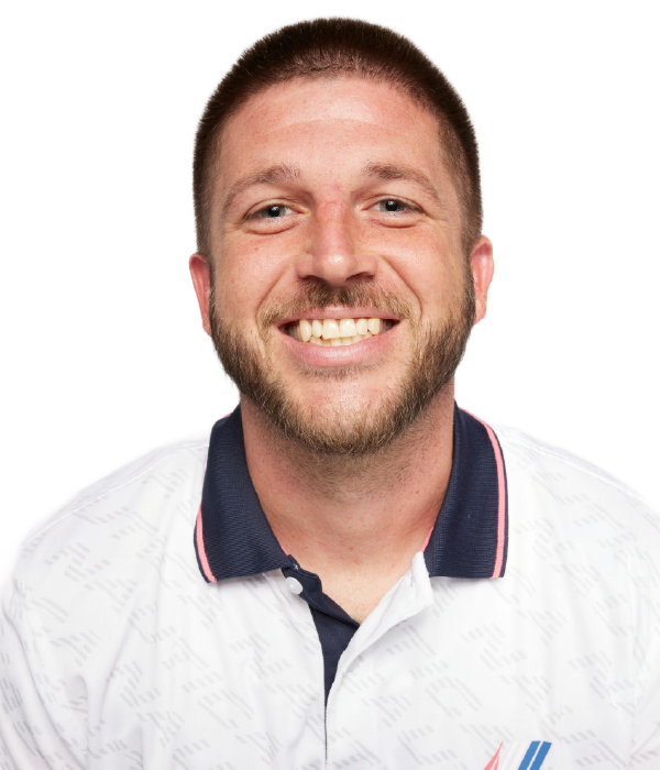 Man with short hair wearing a white polo with blue collar smiling at camera against a white background.