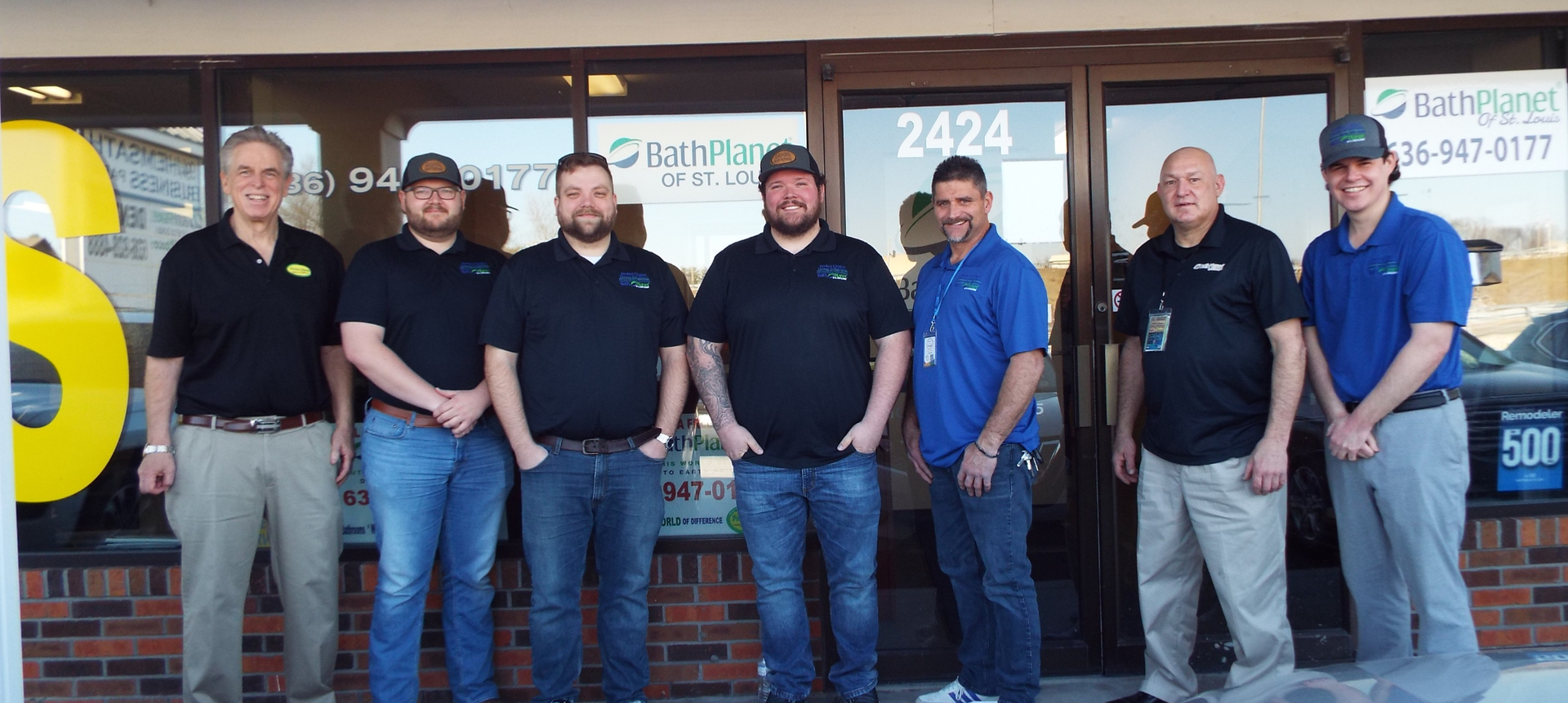 Seven people standing in front of a building with glass doors, brick facade, and the number 2424 above. At Perfect Choice Home Solutions.