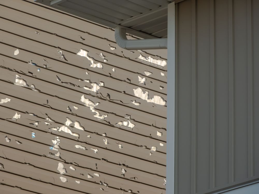Weathered siding with peeling paint next to smooth, unpainted siding; white gutter.