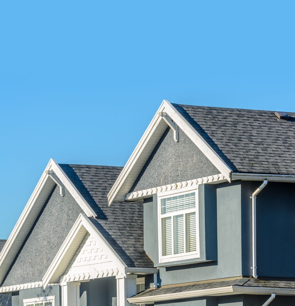 Gray house with white trim, against a blue sky.