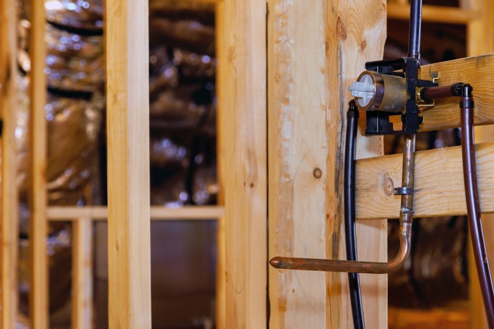 Framed wooden walls with exposed plumbing for a shower.