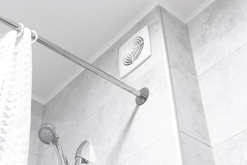Shower interior with showerhead, towel rod, and ventilation fan on tiled wall.