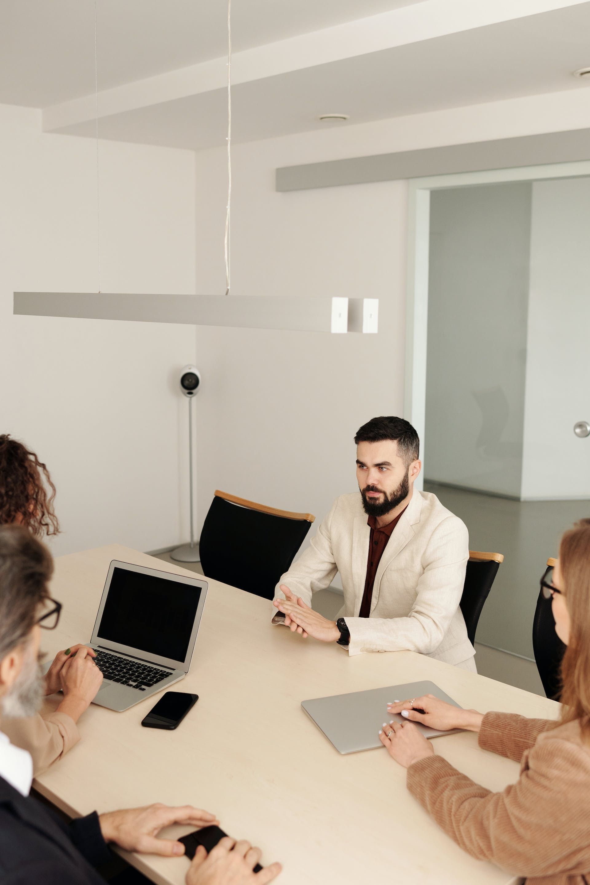 A group of people are sitting around a table with laptops.