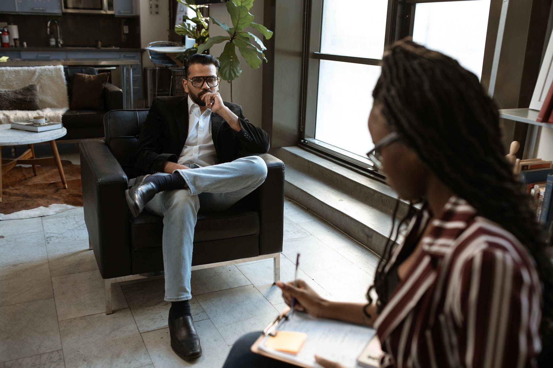 A man is sitting in a chair talking to a woman.