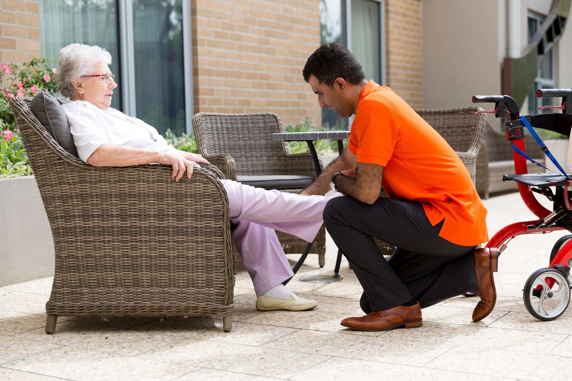 Vivir Healthcare Physiotherapist is kneeling down next to an elderly woman sitting in a chair.