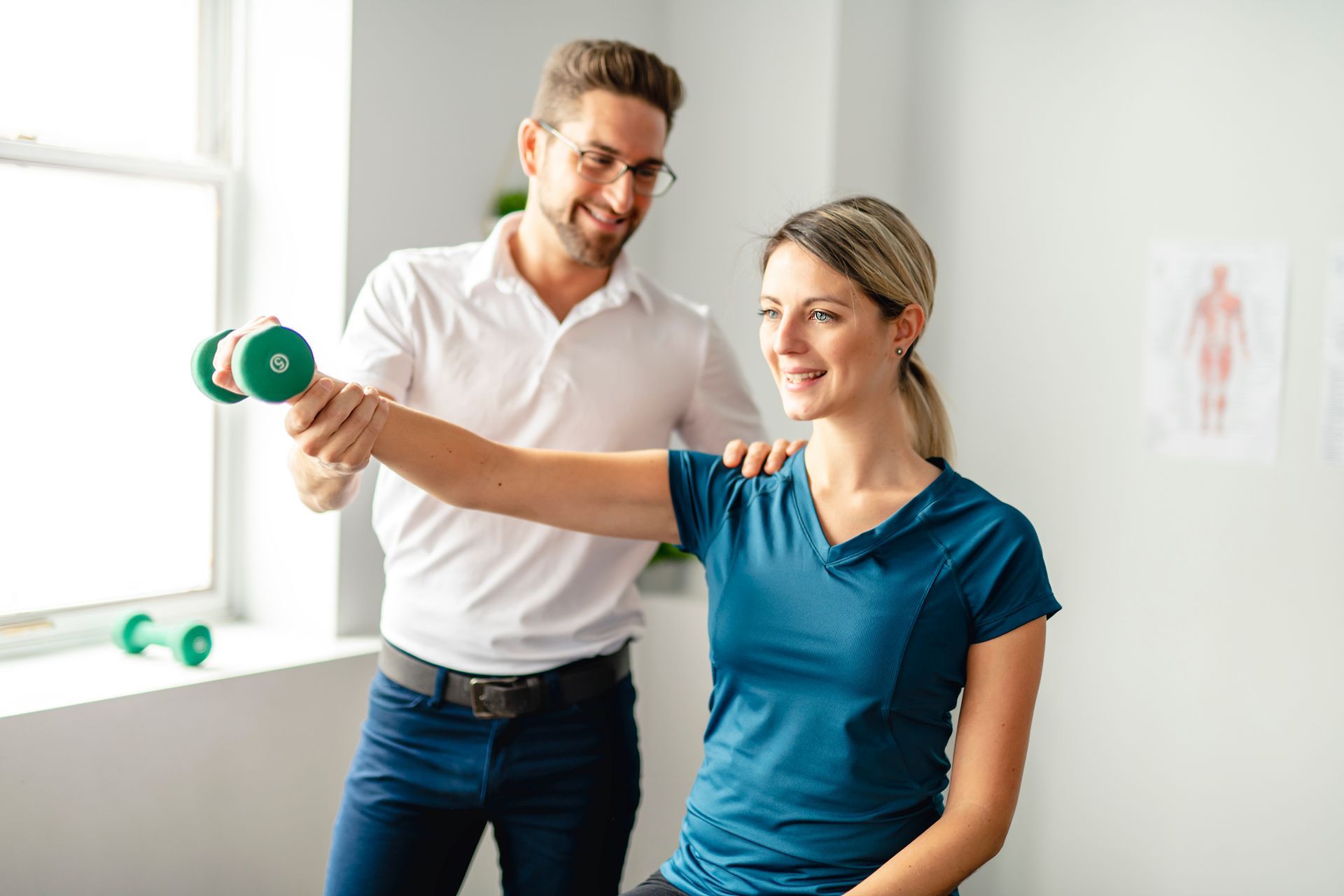 Physiotherapist helping a woman lift a green dumbbell.