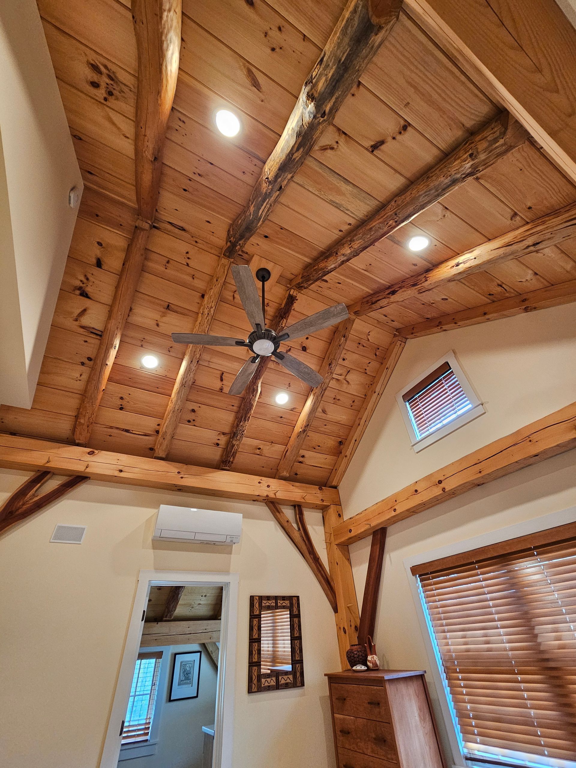 A bedroom with a wooden ceiling and a ceiling fan.