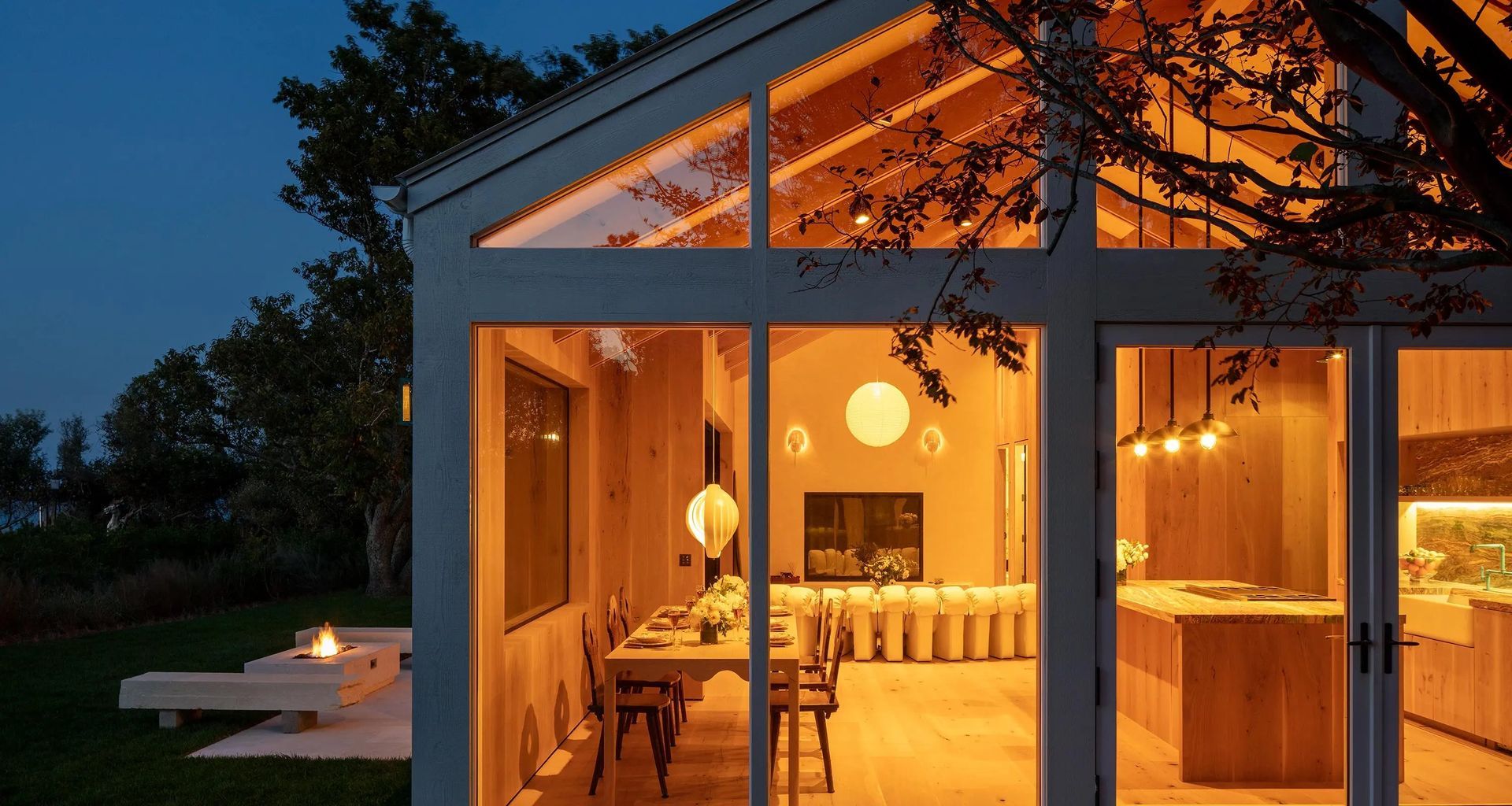 A house with a lot of windows is lit up at night.