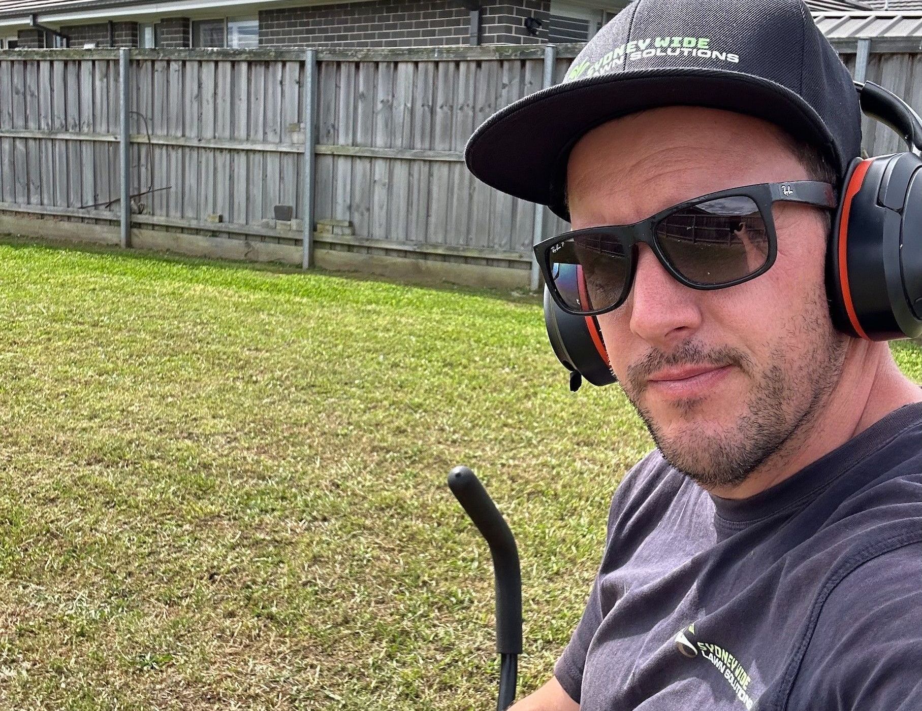 Mowbuddy Daniel sitting on a ride on mower with freshly cut grass in background.
