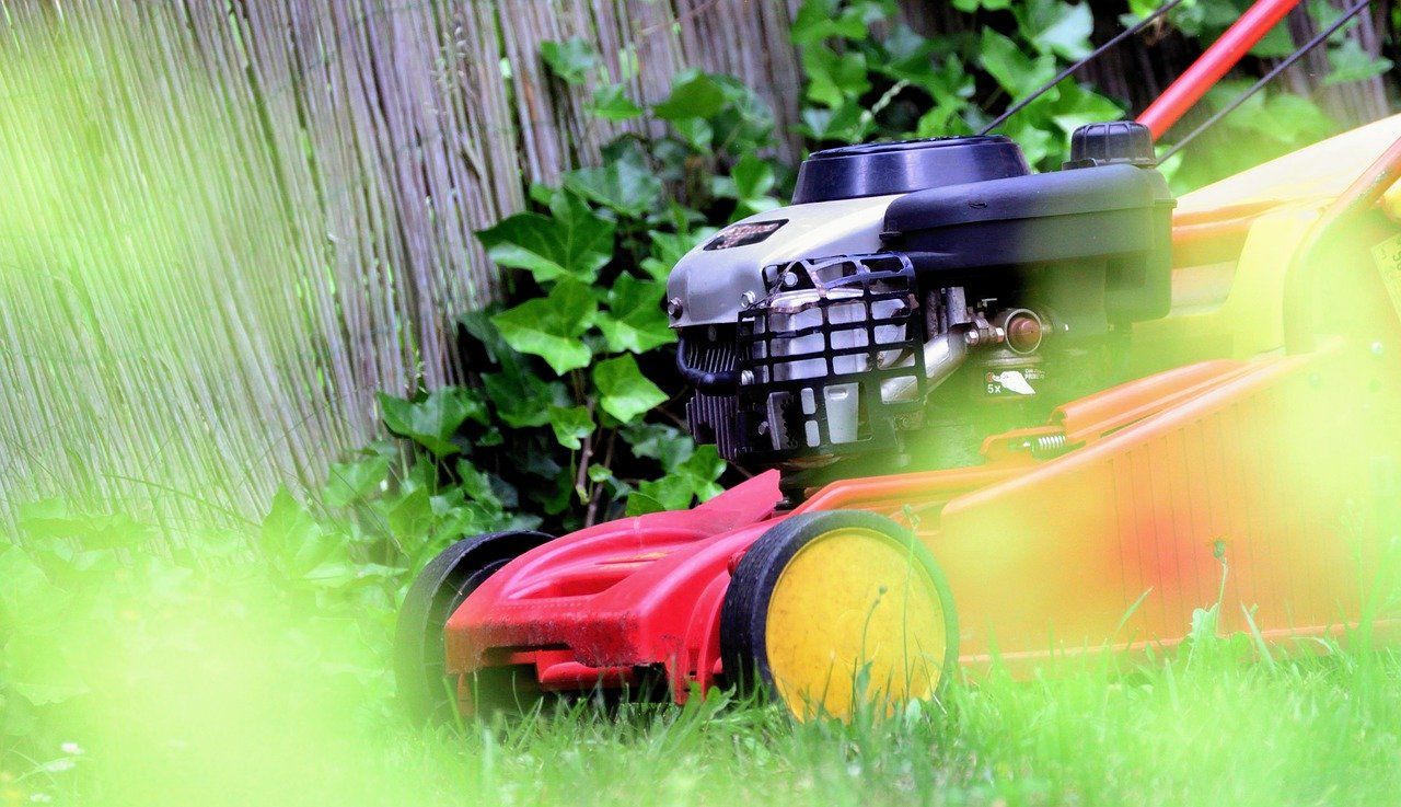 Red lawn mower going over some wet grass