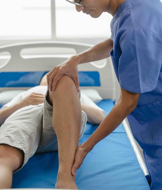 A nurse is examining a patient 's knee in a hospital bed