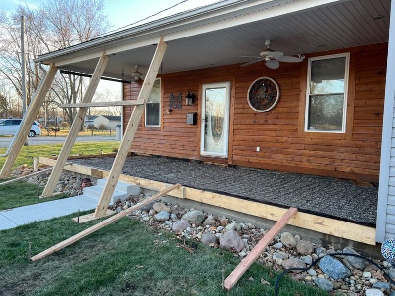 Empty swimming pool with blue speckled lining and steps. Concrete patio surrounds it, houses in background.