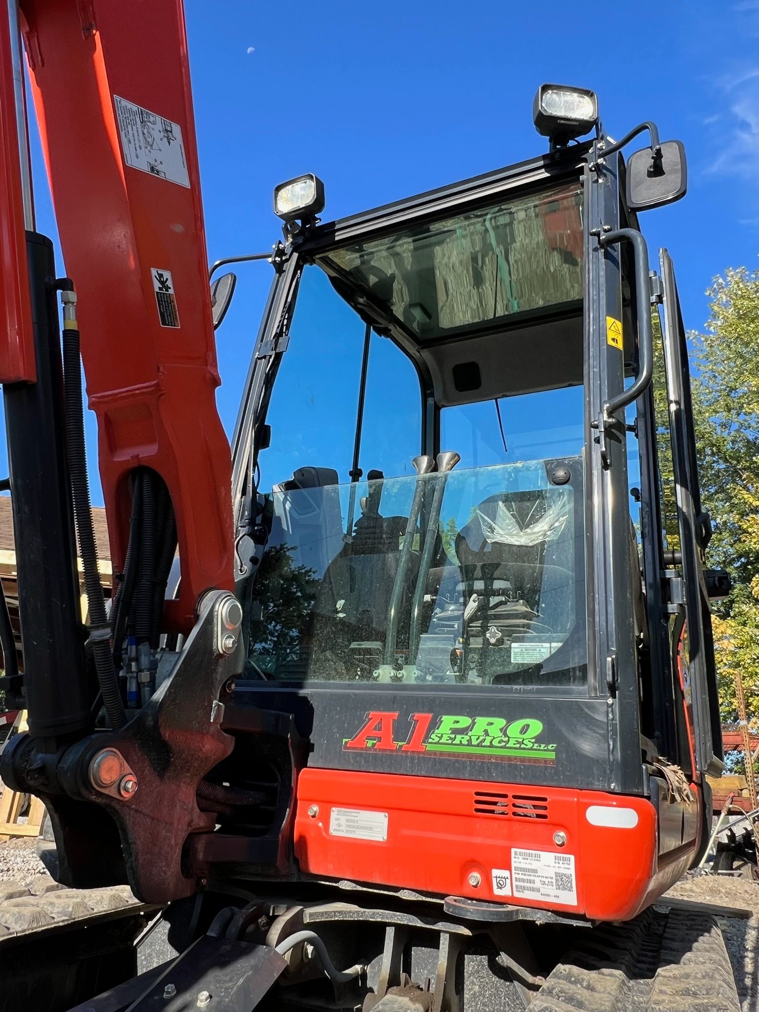 Man digging in an excavated area with a backhoe. Brown earth, orange machinery.