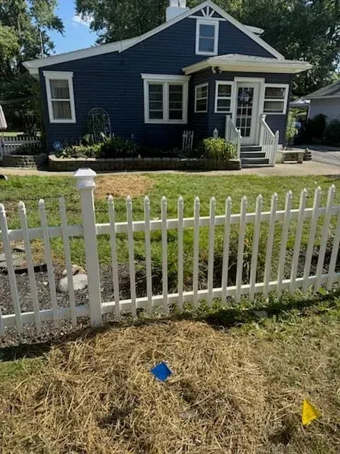 Blue house with white picket fence and dry grass.