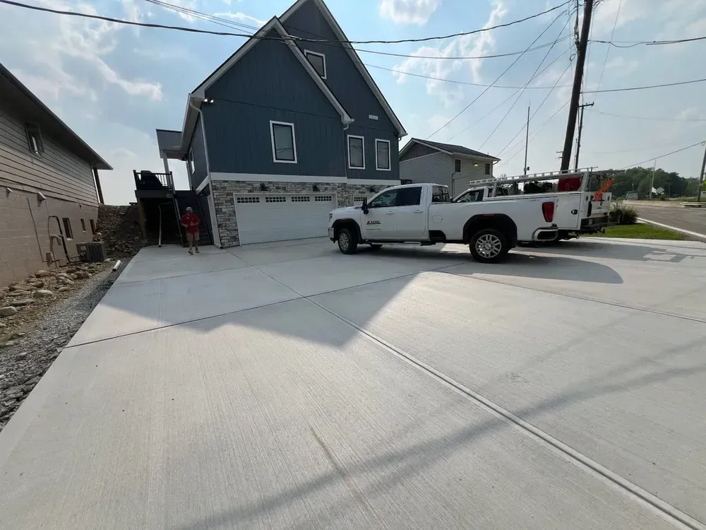 New concrete driveway in front of a blue house with a white truck parked in it.