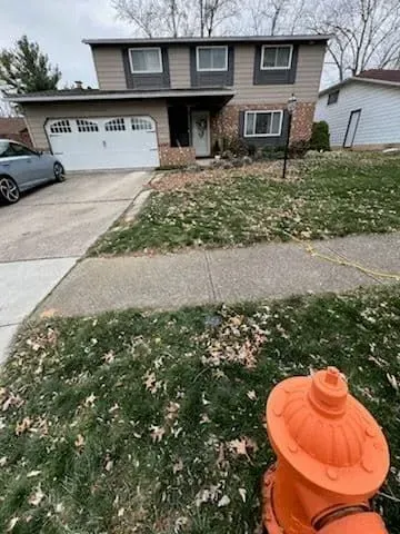 Two-story house with a driveway. An orange fire hydrant is in the foreground. Overcast day.