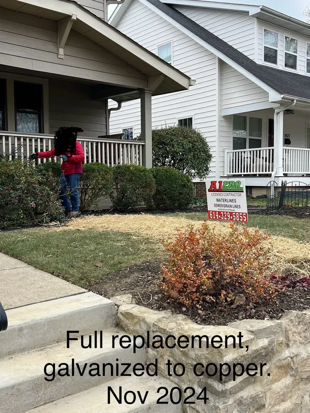 Person working on a lawn in front of a house, with a sign indicating a construction project.