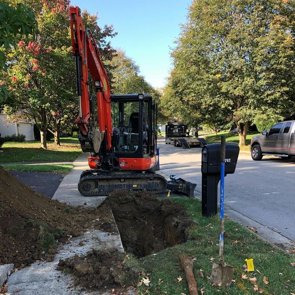 Freshly poured concrete border around a gravel area next to a driveway and landscaping.