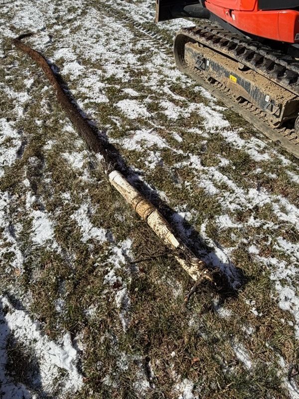 Person working on a lawn in front of a house, with a sign indicating a construction project.